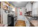 Cozy kitchen featuring classic appliances, white cabinets, and rustic hardwood floors at 309 Ackert Ave, Salisbury, NC 28144