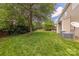 Lush backyard featuring a well-manicured lawn, mature trees, a cozy patio, and visible air conditioning units at 516 Fair Oaks Dr, Fort Mill, SC 29708