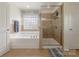 Bathroom featuring a soaking tub, glass enclosed shower, window and tile flooring at 516 Fair Oaks Dr, Fort Mill, SC 29708