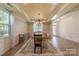 Dining room featuring tray ceilings, a chandelier, wood floors, and wainscoting at 516 Fair Oaks Dr, Fort Mill, SC 29708