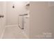 Bright laundry room features modern washer, dryer, storage shelf and tile flooring at 5440 Kinsbridge Dr, Charlotte, NC 28227