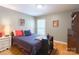 Well-lit bedroom featuring warm hardwood floors, complementing a queen bed with colorful pillows and decor at 6128 Coatbridge Ln, Charlotte, NC 28212