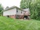 Spacious backyard featuring a raised deck, lush green lawn, brick foundation, and access to a shaded area under the deck at 727 Cove Rd, Gastonia, NC 28052