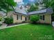 Inviting home featuring a lush green lawn, solar panels, and mature trees at 7521 Surreywood Pl, Charlotte, NC 28270