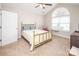 Bright bedroom featuring a vaulted ceiling, ceiling fan, carpeted floors, and an oversized arched window at 8183 Sultana Cir, Charlotte, NC 28227