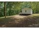 View of backyard with a small white house and concrete patio, surrounded by mature trees at 905 Gantt St, Kings Mountain, NC 28086