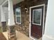 A welcoming front porch with a mahogany front door featuring decorative glass, sidelight, and stone accents at 9730 Tea Garden Dr, Gastonia, NC 28056