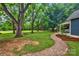 Spacious backyard with lush lawn, picnic table, mature trees and winding stone path leading to covered porch at 9929 Kerns Rd, Huntersville, NC 28078