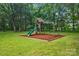 Backyard playground featuring wooden playset with slide and swings, surrounded by lush green lawn and trees at 9929 Kerns Rd, Huntersville, NC 28078