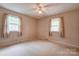 Bedroom with neutral carpet, paneled wallpaper, and two windows with curtains at 105 Hopewell Church Rd, Shelby, NC 28152