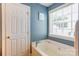 Bright bathroom featuring a soaking tub with a window view, complemented by blue walls and white trim at 1209 Danielle Downs Se Ct, Concord, NC 28025
