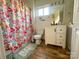Bright bathroom featuring a floral shower curtain, modern vanity, and wood-look flooring at 156 Spruce St, Badin, NC 28009