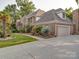 Elegant brick home showing the garage and driveway with a landscaped front yard and mature plantings at 15708 Eagleview Dr, Charlotte, NC 28278