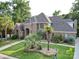 View of the beautiful brick home featuring mature palms and manicured lawn surrounded by mature trees at 15708 Eagleview Dr, Charlotte, NC 28278