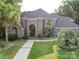Charming brick home featuring a landscaped front yard with mature palm trees and a brick and stone facade at 15708 Eagleview Dr, Charlotte, NC 28278