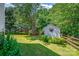Private backyard featuring a storage shed, wooden fence, bench, mature trees, and well-manicured lawn at 167 Foxtail Dr, Mooresville, NC 28117