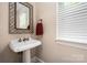 Bathroom featuring pedestal sink with decorative mirror and natural light from a window at 1701 Truman Rd, Charlotte, NC 28205