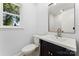 Cozy bathroom featuring a black vanity with a white countertop and framed mirror, complemented by a toilet and window at 18733 Bluff Point Rd, Cornelius, NC 28031