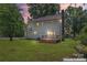A shot of the home's rear exterior showing a chimney and deck with a well-maintained lawn at dusk at 18733 Bluff Point Rd, Cornelius, NC 28031