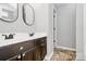 Bathroom featuring dual sinks, dark wood vanity, and tiled flooring, alongside a framed mirror at 1922 Decatur Ct, Charlotte, NC 28213
