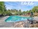 Community pool surrounded by mature trees, lounge chairs, and seating areas under a sunny blue sky at 1922 Decatur Ct, Charlotte, NC 28213