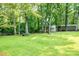 Lush green backyard with mature trees and storage sheds, offering a private and serene outdoor space at 214 Cottage Pl, York, SC 29745