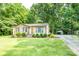 Charming brick home with an orange front door, lush landscaping, and convenient carport, surrounded by trees at 214 Cottage Pl, York, SC 29745