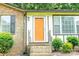 Inviting entryway with a bright orange door, brick steps, and manicured shrubs for a welcoming touch at 214 Cottage Pl, York, SC 29745