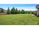 Lush, well-maintained backyard with a wooden fence, mature trees, and a patio area with grill at 246 Bushney Loop, Mooresville, NC 28115