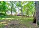 View of the home in a lush, green backyard surrounded by big, mature trees with a wooden deck at 3043 Charles Rd, Shelby, NC 28152