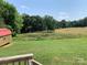 View of the backyard barn with a red roof with vast green space creating a tranquil outdoor setting at 6219 Heavner Rd, Vale, NC 28168