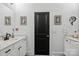 Bright bathroom featuring double vanity, white cabinets, framed fern art, and black door at 6438 Hove Rd, Mint Hill, NC 28227