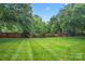 Expansive backyard with manicured lawn and mature trees offers plenty of space for outdoor activities and relaxation at 6632 Hawksnest Dr, Charlotte, NC 28269