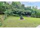 Lush backyard with a well-manicured lawn, mature trees, and a charming fire pit area for entertaining at 7434 Dover Mill Sw Ln, Concord, NC 28025