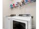 Bright laundry room equipped with a modern washer and dryer set, with overhead shelving at 7434 Dover Mill Sw Ln, Concord, NC 28025