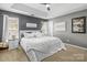 A stylish main bedroom featuring neutral tones, a tray ceiling, and plush white bedding at 7881 Mariners Pointe Cir, Denver, NC 28037