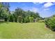 Expansive backyard with a well-manicured lawn, mature trees, and secure fencing at 8340 Breton Way, Harrisburg, NC 28075