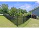 Private backyard enclosed by a black iron fence, featuring mature trees and lush landscaping at 8340 Breton Way, Harrisburg, NC 28075