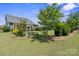 Serene backyard with mature trees, a cozy bench, and beautifully landscaped garden beds at 8340 Breton Way, Harrisburg, NC 28075
