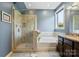 Bright bathroom with a glass shower, soaking tub, and a large window for natural light at 8340 Breton Way, Harrisburg, NC 28075
