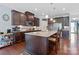 A spacious kitchen featuring a large island, dark cabinets, stainless steel appliances, and hardwood floors at 8340 Breton Way, Harrisburg, NC 28075