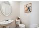 Modern powder room has a pedestal sink, toilet, decorative mirror and attractive art at 925 Skywatch Ln, Monroe, NC 28112