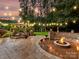 Beautiful backyard patio with a fire pit, elegant stone seating, ambient string lights and mature landscaping at 105 Beech Bluff Dr, Mount Holly, NC 28120