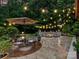 Outdoor patio with seating, an umbrella, a fire pit, string lights, and professional landscaping at 105 Beech Bluff Dr, Mount Holly, NC 28120