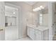 Bright bathroom featuring a white vanity, a large mirror with vanity lights, and access to a bright living area at 11723 Oakland Hills Pl, Charlotte, NC 28277