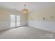 Large bedroom with a stylish chandelier and French doors that lead to an outdoor balcony with natural light at 11723 Oakland Hills Pl, Charlotte, NC 28277