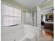 Bathroom featuring a whirlpool tub, glass enclosed shower, and natural light at 11909 Creek Turn Dr, Charlotte, NC 28278