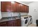 Well-equipped laundry room with sleek, dark cabinets, a utility sink, granite countertops and modern washer and dryer at 15018 Marymont Ave, Huntersville, NC 28078