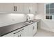 Well-equipped laundry room with modern cabinets, dark countertops, and sleek fixtures at 213 Crest Ct, Weddington, NC 28104