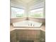 Bathroom with a large triangular soaking tub is surrounded by tiled walls and two windows at 2634 Treeline Dr, Concord, NC 28027